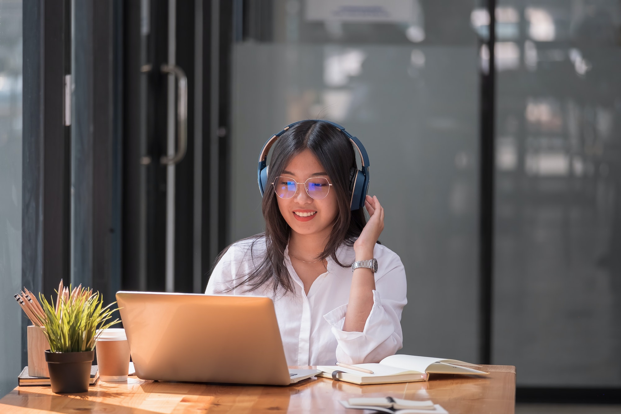 Asian girl with glasses look at laptop while doing homework making video call abroad using internet